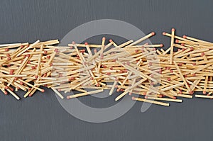 Row of many matches with red sulfur on dark concrete desk on kitchen. Top view