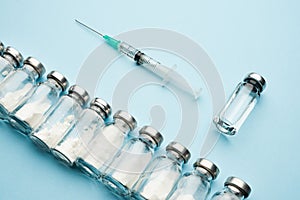 Row of medical vials and syringe. Glass bottles with powder for injection and one with transparent potion on a light