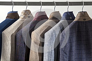 Row of men`s suits hanged on a rack, isolated on white background. Men`s wear collection