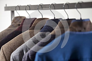 Row of men`s suits hanged on a rack, isolated on white background. Men`s wear collection