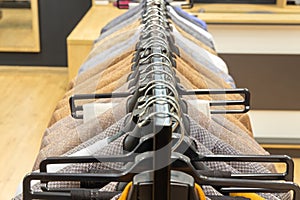 A row of men\'s suits, jackets hanging on a rack for display