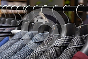 A row of men\'s suits, jackets hanging on a rack for display