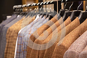 A row of men\'s suits, jackets hanging on a rack for display