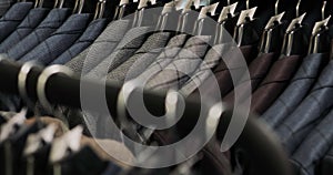 Row of men suit jackets on hangers. Collection of new beautiful clothes hanging on hangers in a shop.