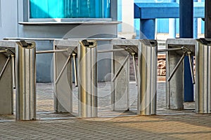 A row of metal turnstiles on the sidewalk at the station