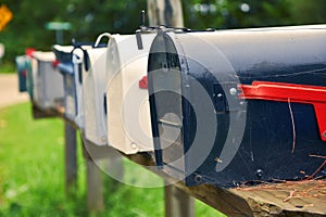 An  row of metal US mail boxes on wooden post in the countryside. Spider webs in one of them. Mail concept. New York City