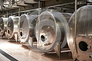 A row of metal vats in a modern winemaking facility