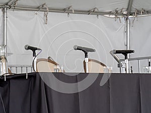 Row of microphones sitting on table, awaiting speakers
