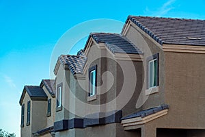 Row of modern house buildings in late afternoon shade with desert adobe colors brown and beige in modern neighborhood