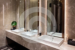 Row of modern marble ceramic wash basin in public toilet, restroom in restaurant or hotel or shopping mall, interior decoration