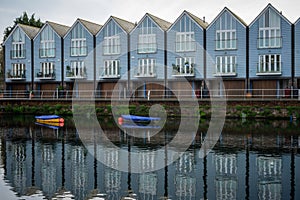 A row of modern townhouses overlooking a river reflecting on the water