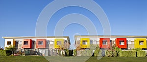 Row of modern townhouses with vibrant red and yellow enclosed balconies