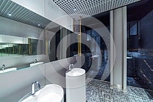 Row of modern white ceramic wash basin in public toilet with cityscape background, restroom in restaurant or hotel or shopping