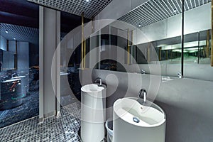 Row of modern white ceramic wash basin in public toilet with cityscape background, restroom in restaurant or hotel or shopping