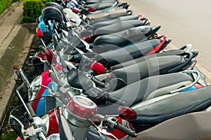 In a row of mopeds parked at the sidewalk