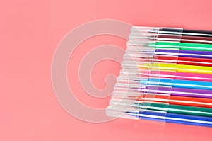 Row of multi colored felt pens lies on pink desk in kindergarten
