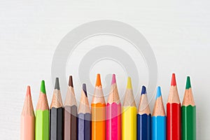 Row of multicolored rainbow palette pencils on white wood background. Art presentation creativity hobbies sketching lettering