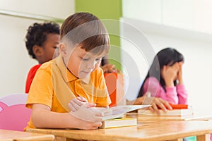 Row of multiethnic elementary students reading book in classroom. Vintage effect style pictures