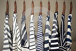 A row of navy striped tops for women on wooden hangers in a closet