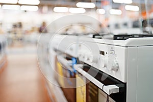 Row of new gas stoves in electronics store, nobody