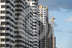 Row of new multi apartment houses and construction crane