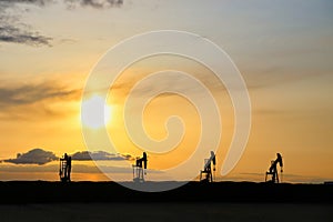 A row of oil pumpjacks at sunset