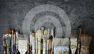 Row of old artist paintbrushes on a dark gray decorative stucco surface