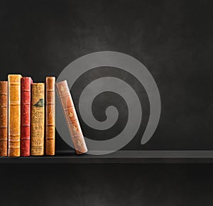 Row of old books on black shelf. Square background