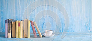 Row of old books and a cup of coffe on a rustic table panorma,r photo