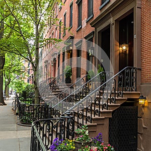 Row of old brownstone buildings along an empty sidewalk block in the Greenwich Village neighborhood of Manhattan, New