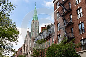 Row of Old Colorful Brick Residential Buildings with a Church along a Street in Chelsea of New York City