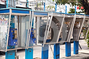 Row of old dirty payphones on a street in Thailand. Group of blu