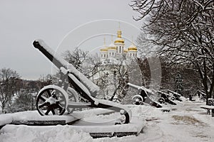 Row of old metal cannons covered with snow in winter park