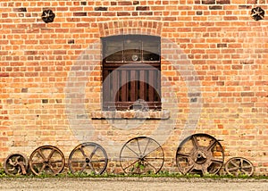 Row of old rusty cart wheels against barn