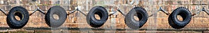 Row of old tires chained together against a stone pier as ship bumpers