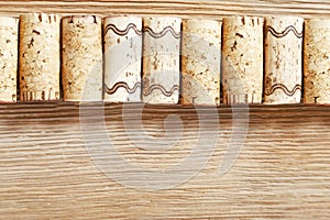 A row of old wine corks on a wooden background.