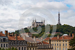 Row of older buildings in Lyon, France with La Basilique Notre Dame and Metallic tower behind the in