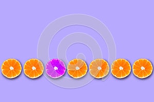 Row of orange cut tangerines with violet one. Concept of being unique and creative.