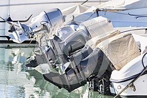 A row of outboard nautical engines mounted on fiberglass boats