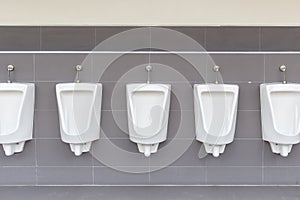 Row of outdoor urinals on grey wall in men public toilet