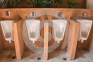 Row of outdoor white urinals men in public toilet.