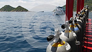 Row of oxygen tanks and diving equipment placed on modern boat in rippling ocean near Koh Tao resort, Thailand. Concept