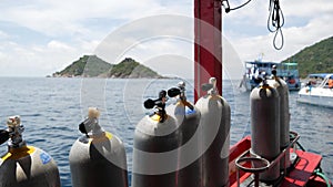 Row of oxygen tanks and diving equipment placed on modern boat in rippling ocean near Koh Tao resort, Thailand. Concept