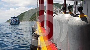 Row of oxygen tanks and diving equipment placed on modern boat in rippling ocean near Koh Tao resort, Thailand. Concept