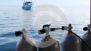 Row of oxygen tanks and diving equipment placed on modern boat in rippling ocean near Koh Tao resort, Thailand. Concept