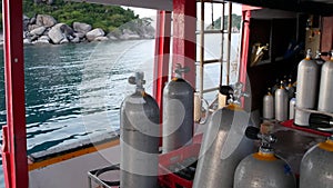 Row of oxygen tanks and diving equipment placed on modern boat in rippling ocean near Koh Tao resort, Thailand. Concept