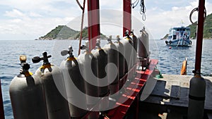 Row of oxygen tanks and diving equipment placed on modern boat in rippling ocean near Koh Tao resort, Thailand. Concept