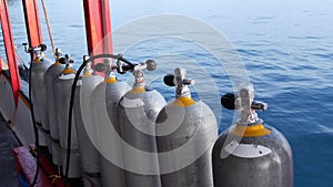 Row of oxygen tanks and diving equipment placed on modern boat in rippling ocean near Koh Tao resort, Thailand. Concept of tourist