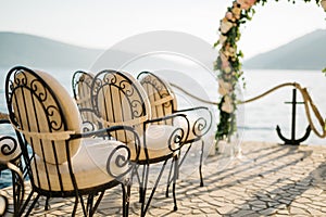 Row of padded chairs in front of a wedding arch on a cobbled pier