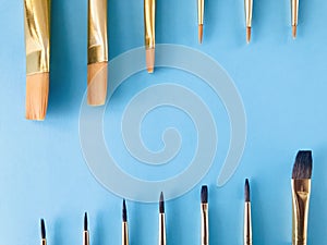 Row of Paint brushes on light blue background. copy space.